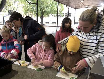 Eltern und Lehrer beim Apfel schneiden und pressen