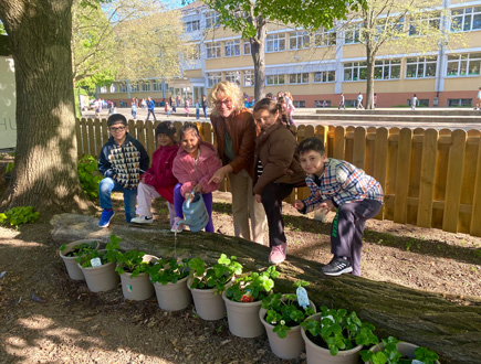 Lehrer und Schüler beim gärtnern und gießen von Erdbeeren